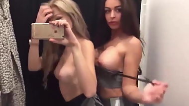 two beautiful girls kiss and caress each other in a fitting